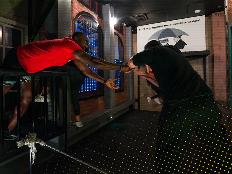 Two players reaching through the barred window of the Bank Heist room