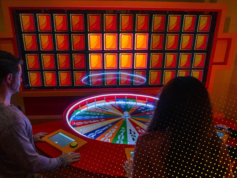 Players at the spinning wheel and light board of the Game Show room